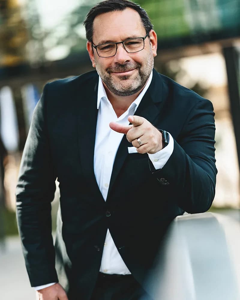 Thomas Dötzl zeigt lächelnd in die Kamera